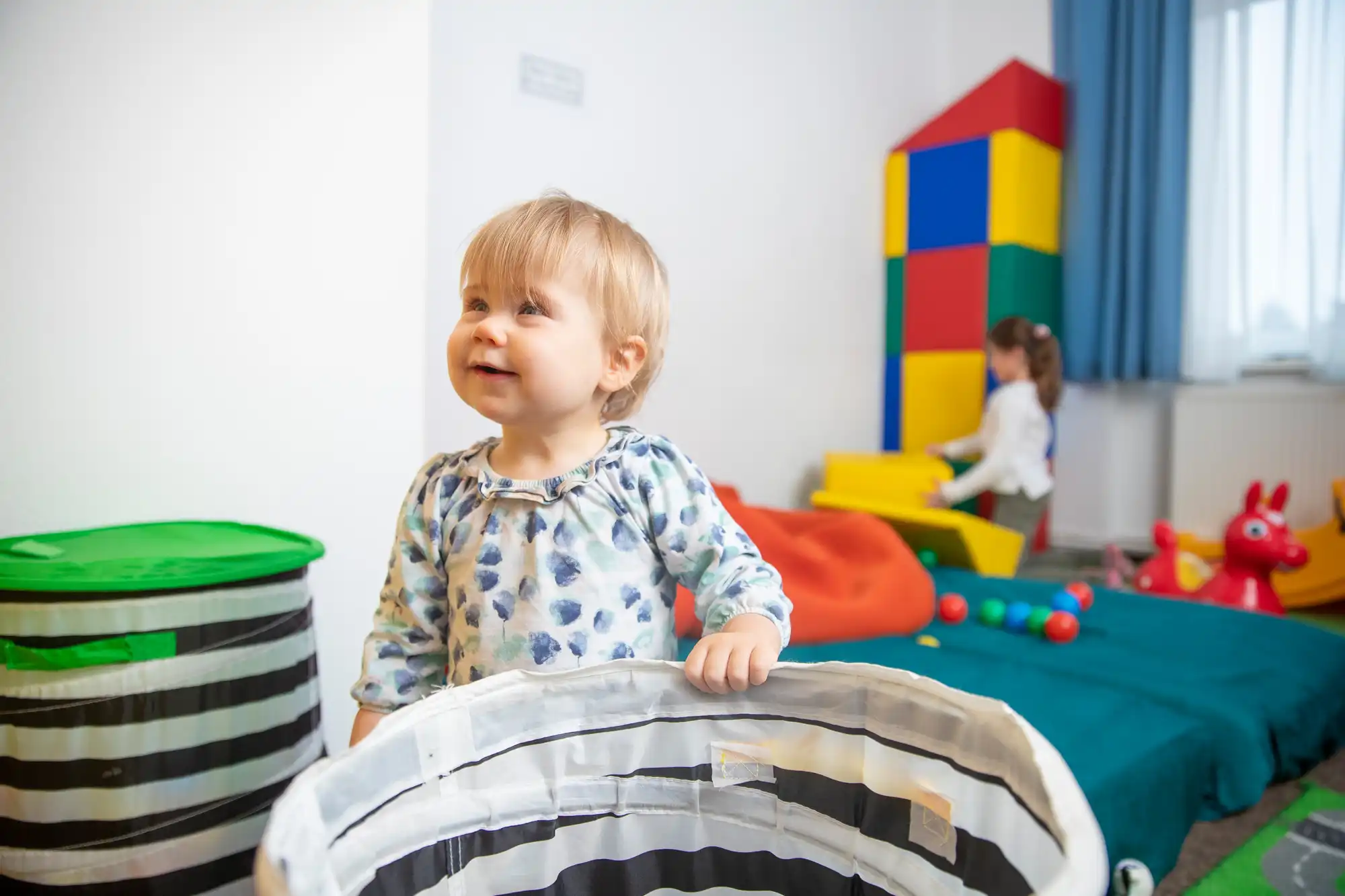 Kleinkind erkundet das kindgerecht ausgestattete Spielzimmer mit buntem Spielzeug und sicherem Mobiliar